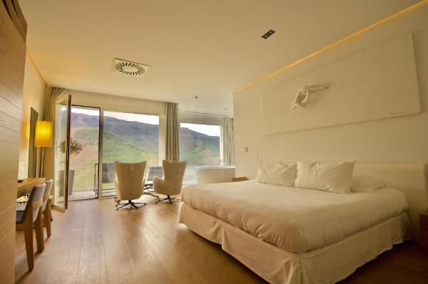 Chambre d'hôtel avec grande fenêtre, lit, fauteuils et baignoire circulaire
